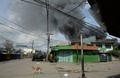 イスラム武装勢力の襲撃を受けたフィリピン南部ミンダナオ（Mindanao）島の商業都市サンボアンガ（Zamboanga）では、12日も治安当局と和平協議に応じないイスラム反政府勢力との戦いが2か所の戦線で続いている。同国政府は、炎に包まれた複数の地区を奪還した。

サンボアンガでは、4日間にわたる戦闘で数千人が避難を強いられている。フィリピン軍報道官によると、同市のサンタカタリナ（Santa Catalina）地区では、治安部隊が進軍する中、家々が炎に包まれた。

警察の支援を受けた少なくとも1500人の兵士が、サンボアンガ郊外のイスラム教徒が多く住む6地区を包囲。これらの地域では、反政府勢力「モロ民族解放戦線（MNLF）」のメンバー約180人が、9日に攻撃を開始して以降潜伏を続けている。反政府勢力は数十人の人々を「人間の盾」にしているため、市民が負傷することを避けたい治安部隊との間でこう着状態が続いている。

写真はサンボアンガで、煙を上げる家々の近くで反政府勢力に向け発砲する兵士ら（2013年9月12日撮影）。(c)AFP/TED ALJIBE