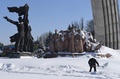 ウクライナの首都キエフで、夜間の大雪の後、雪かきをする人。後ろの像はウクライナとロシアの連帯を示すソビエト時代のモニュメント（2018年3月2日撮影）。(c)AFP PHOTO / Sergei SUPINSKY