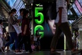タイの首都バンコクの駅で、5G通信の広告の前を歩く人々（2020年5月5日撮影、資料写真）。(c)Mladen ANTONOV / AFP